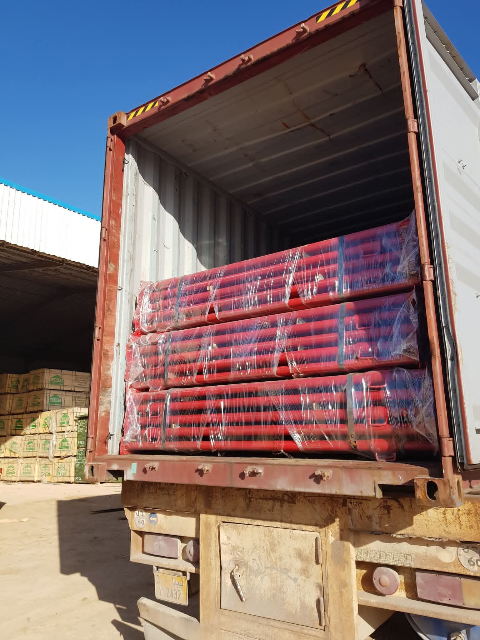 حاوية شحن تحتوي على أنابيب معدنية حمراء - شركة المداد